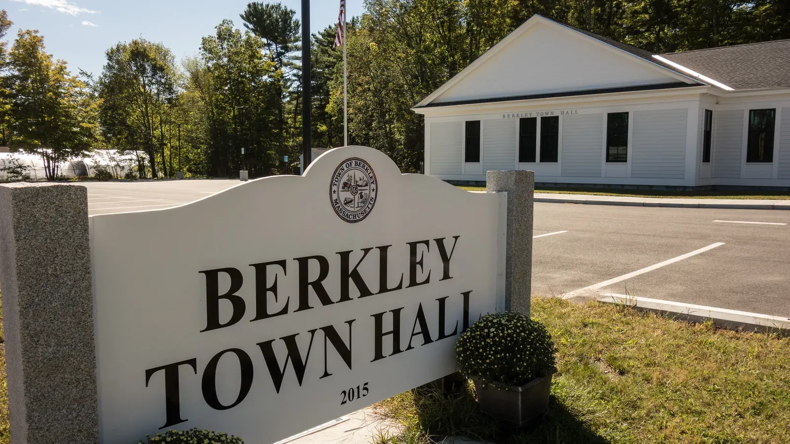The granite-framed Berkley Town Hall sign in front of the white town hall building, Berkley, Massachusetts