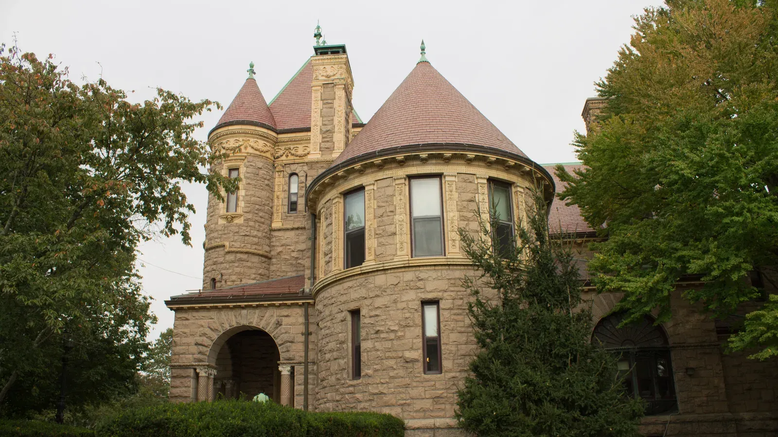 The Millicent Library, a Romanesque stone library with conical-roofed turrets and an arched entrance framed by trees, Fairhaven, Massachusetts