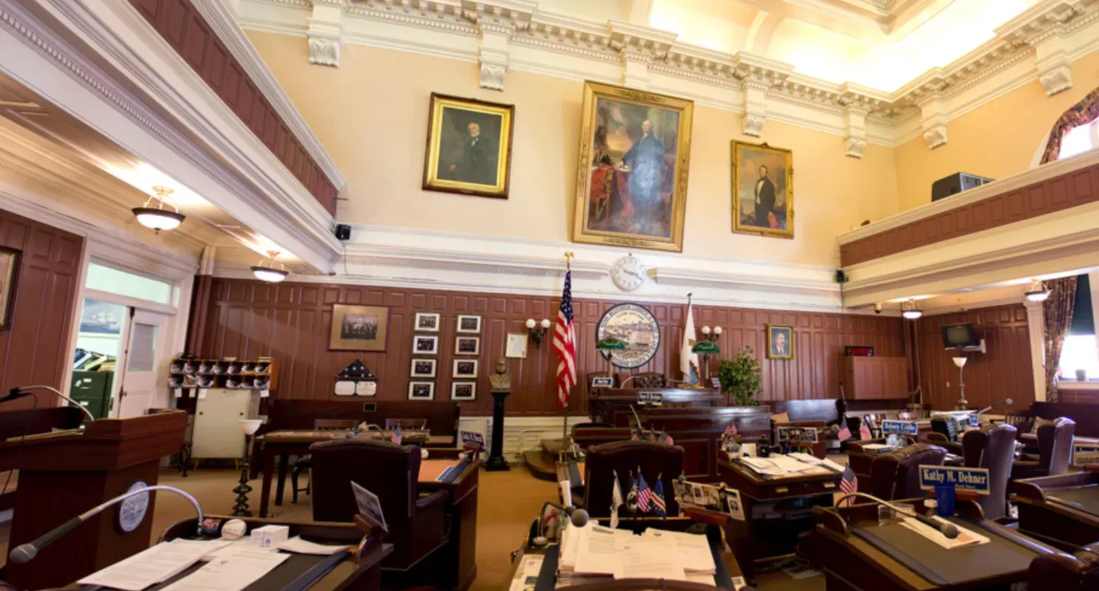 New Bedford City Council chamber in City Hall, Massachusetts: a coffered plaster ceiling with ornate cornice, plaster-finished walls above wood wainscoting, and the city seal behind the rostrum